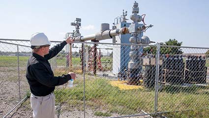 male field utility worker looking at large-scale CO2 injection equipment at a saline formation in the Illinois Basin.